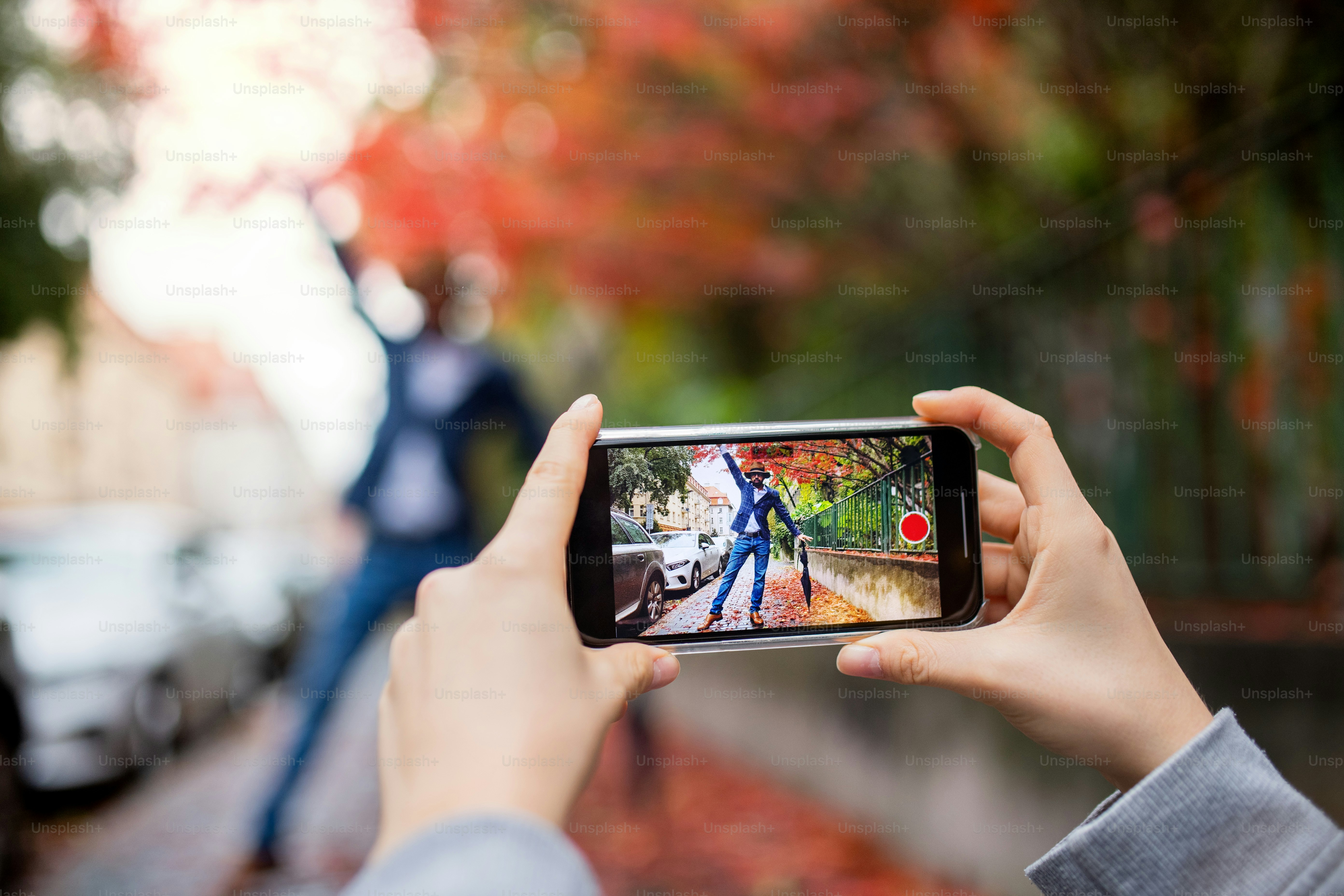 A young couple with smartphone making video for social media outdoors on street